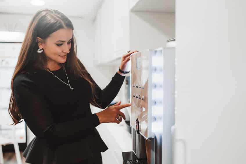businesswoman using a coffee machine indoors
